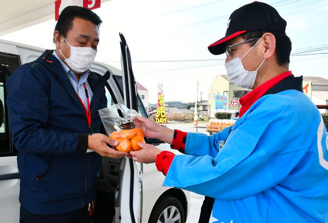 日頃の感謝の気持ちを込め、利用者(写真㊧)にミカンを手渡すJA職員