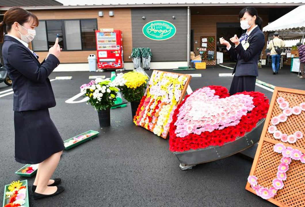 ガーベラをあしらったモニュメントの前で記念撮影をする来店者