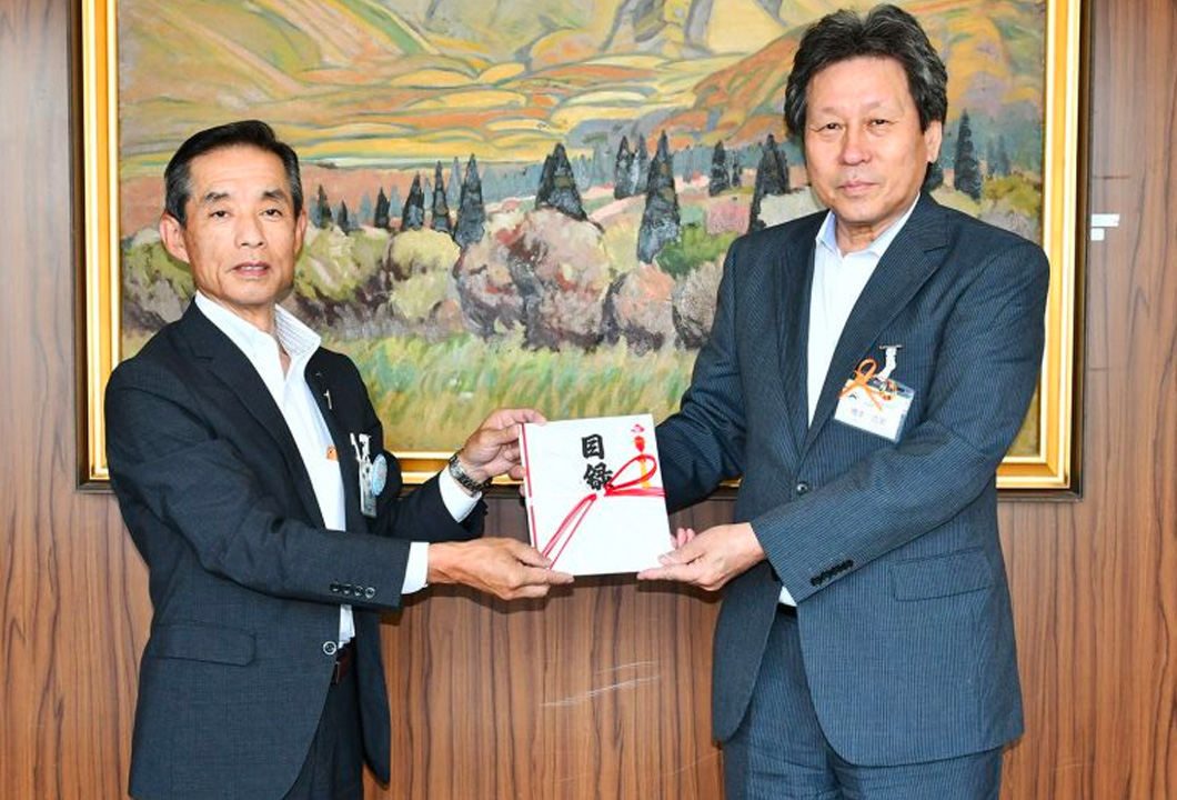 橋本教育長へ図書カードを贈呈する小松常務（写真左）