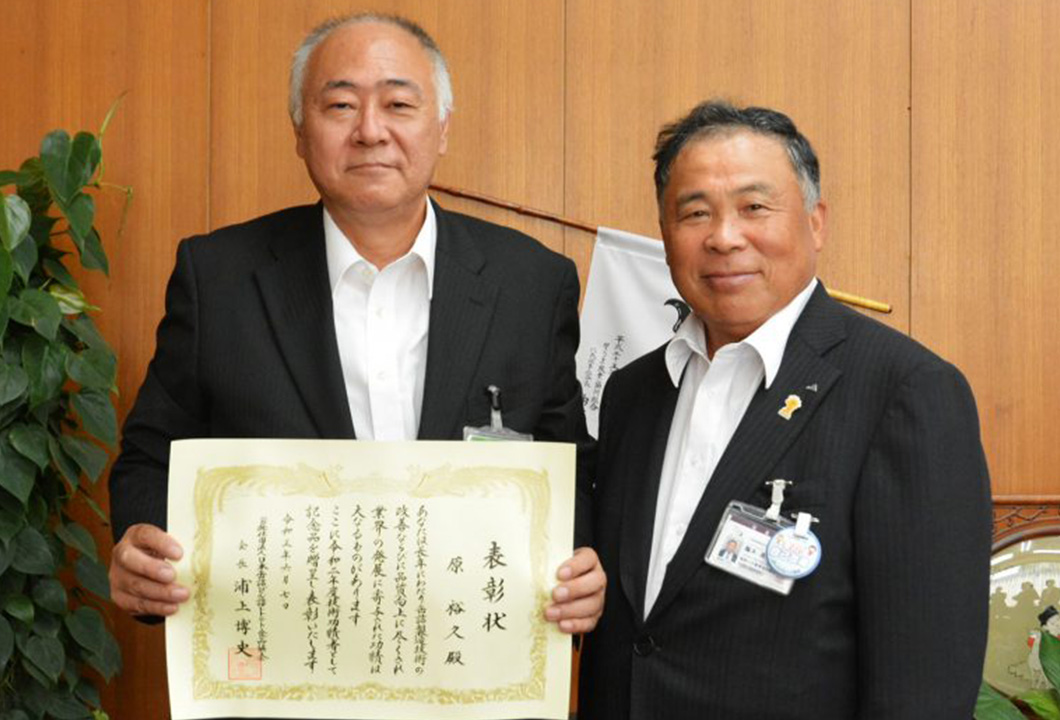 鵜木組合長(写真㊨に受賞を報告する原さん)