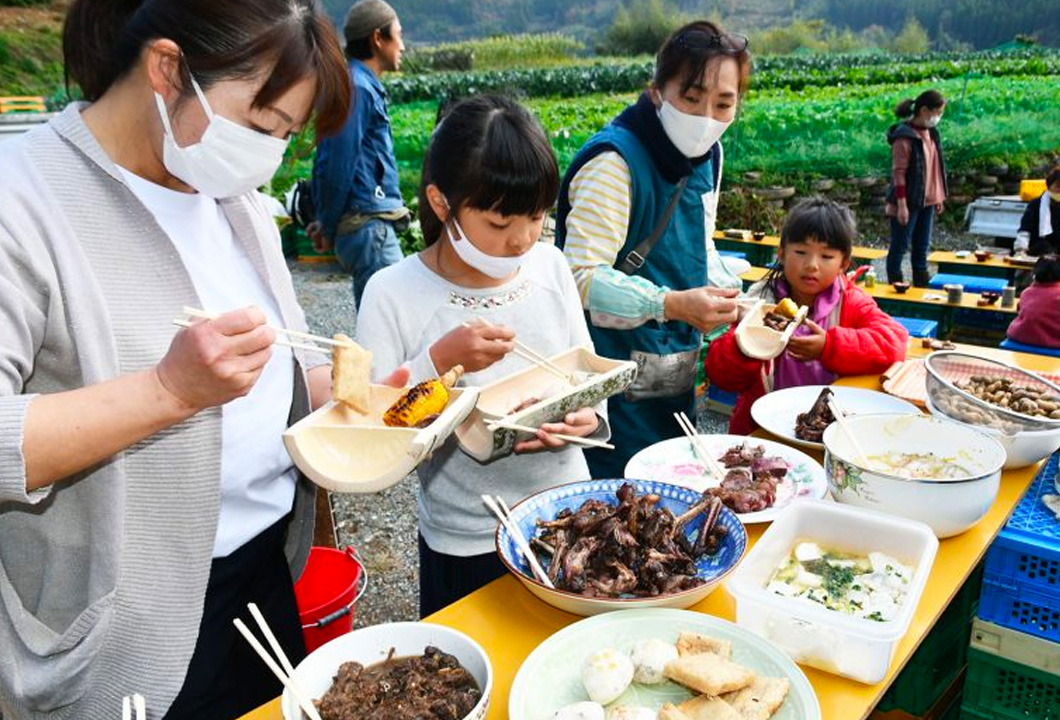 採れたての野菜などを使った料理を取り分ける参加者